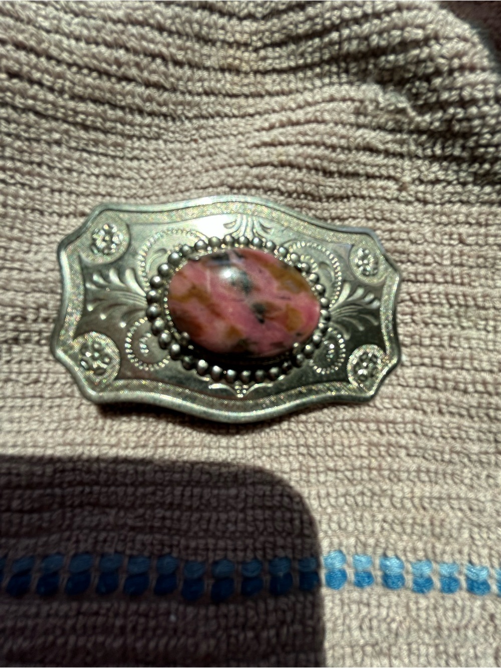 Ornate silver belt buckle with a pink and black rhodonite